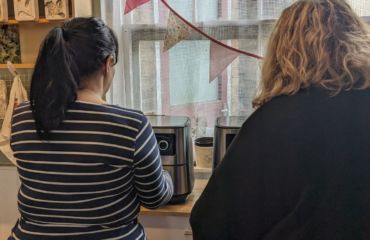 The backs of two ladies using the air fryers