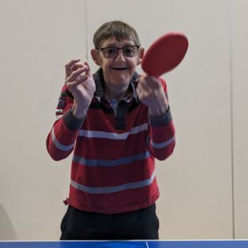 A man holding a table tennis bat and ball