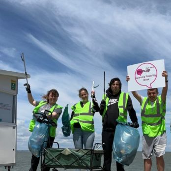 People wearing high vis jackets holding litter picks