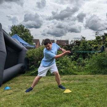 Man in blue top swinging a golf club in the garden