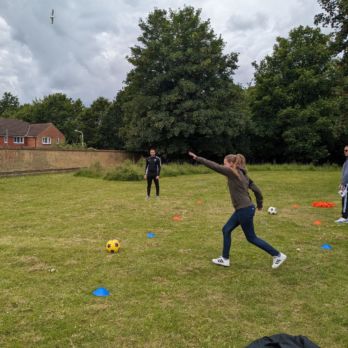 A lady about to kick a football in the field