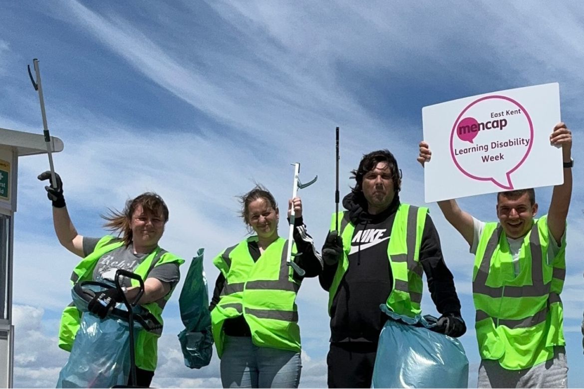 Four people wearing high vis jackets and holding litter picks and a Learning Disability Week sign