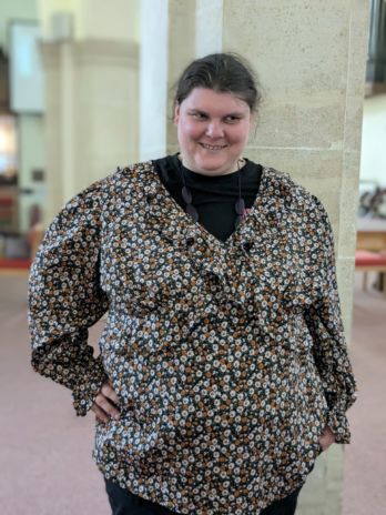 Lady smiling in her outfit in front of a pillar