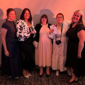 Group shot of five ladies dressed smartly and one holding an award