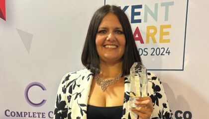 Vicki holding her award and smiling