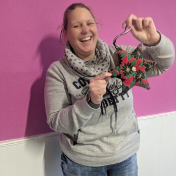 Lady smiling holding a star against a pink wall