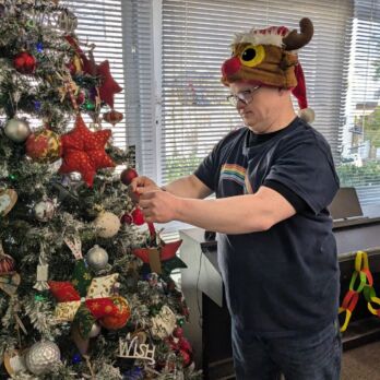 Man putting star on Christmas tree wearing a festive hat